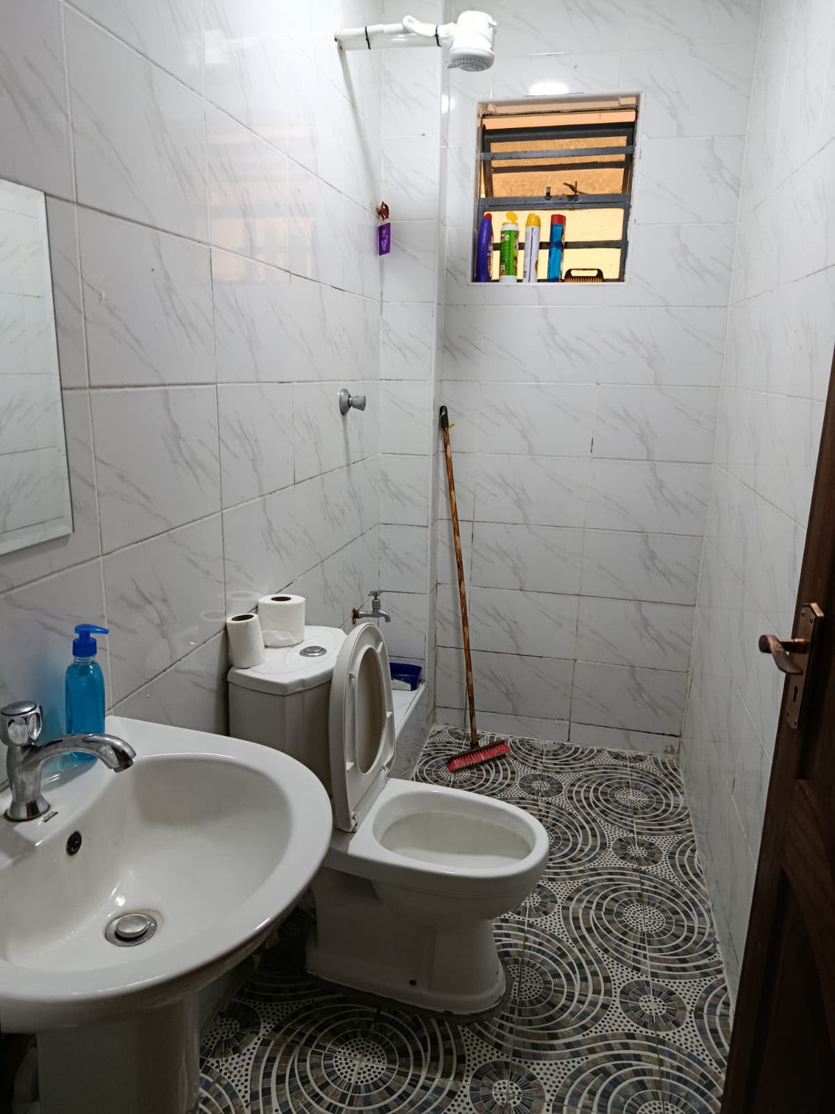 Tiled bathroom with hot shower, toilet and washbasin