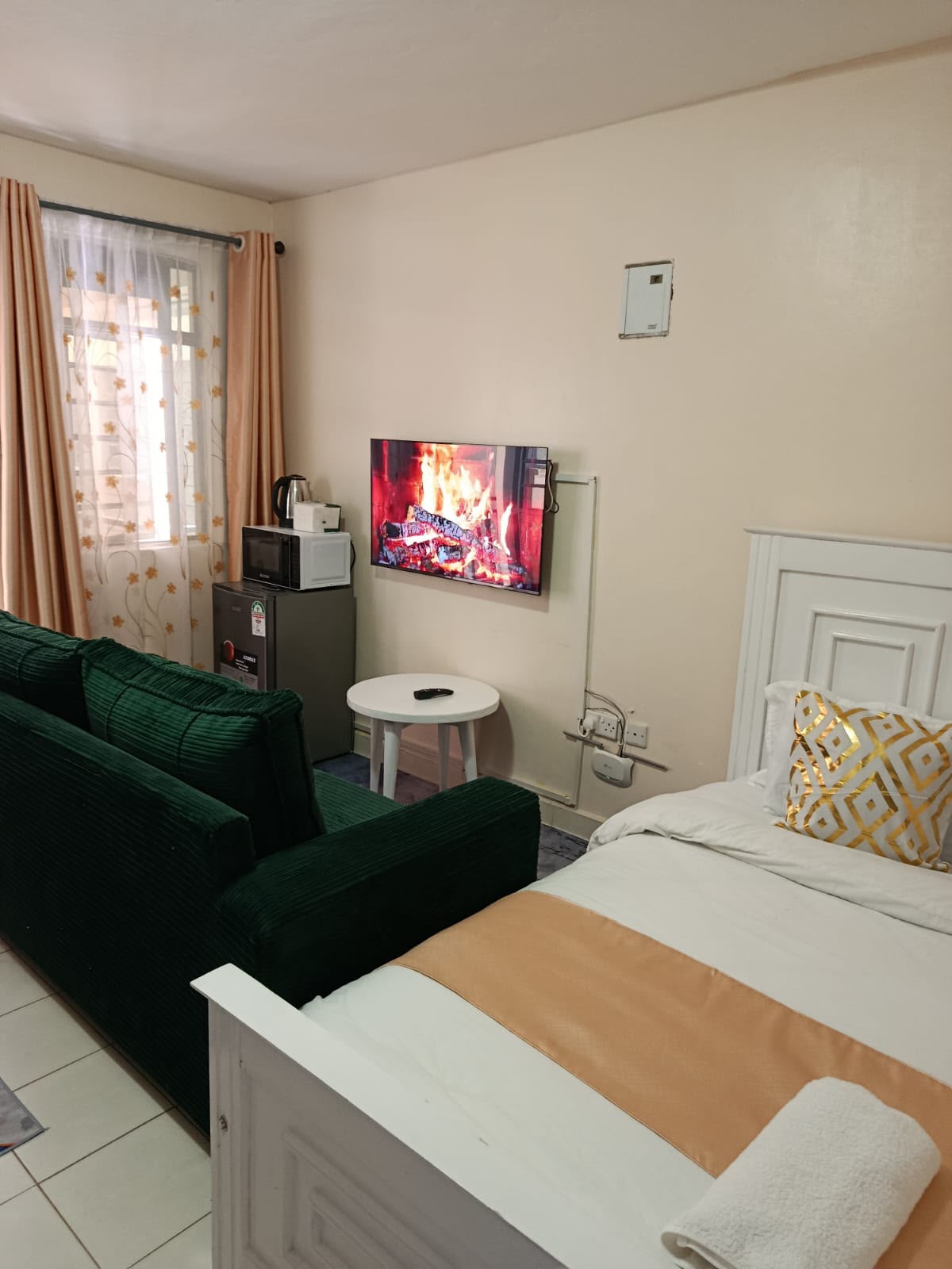 Studio lounge with green sofa, smart TV, fridge and microwave