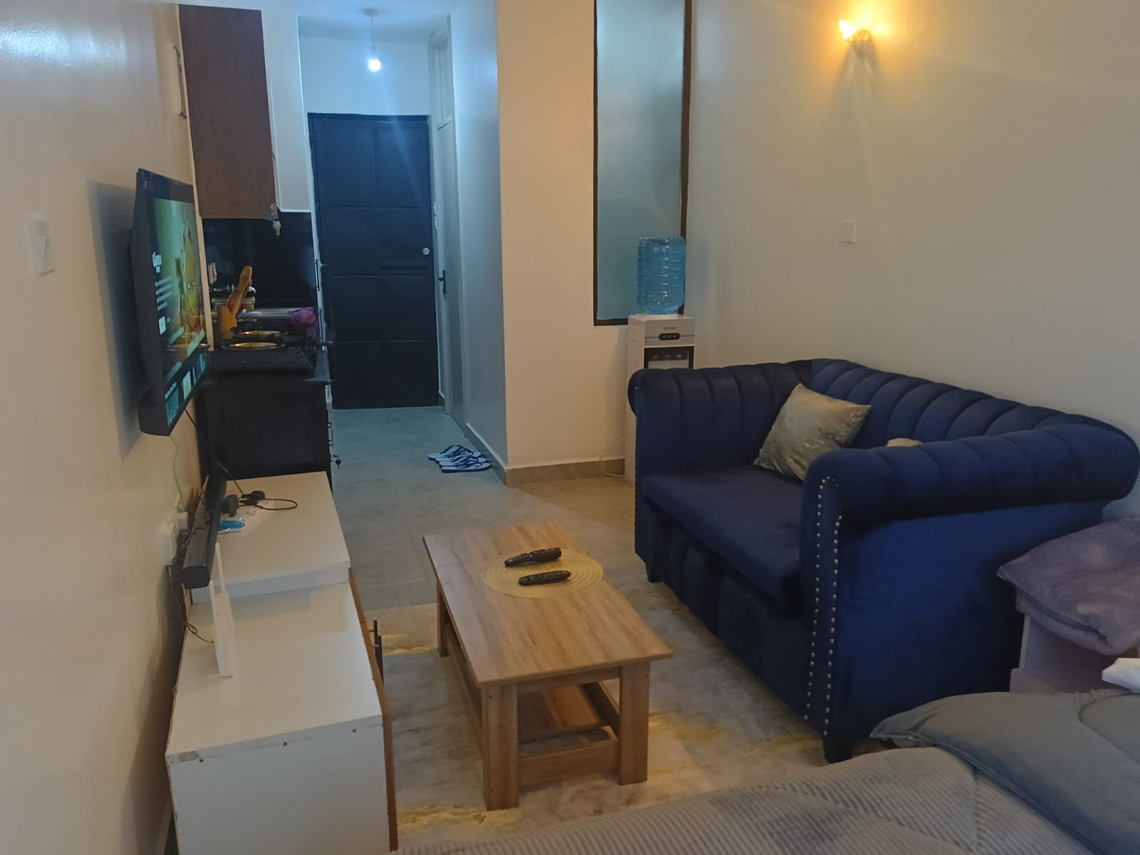 Lounge area with blue chesterfield sofa, coffee table and smart TV